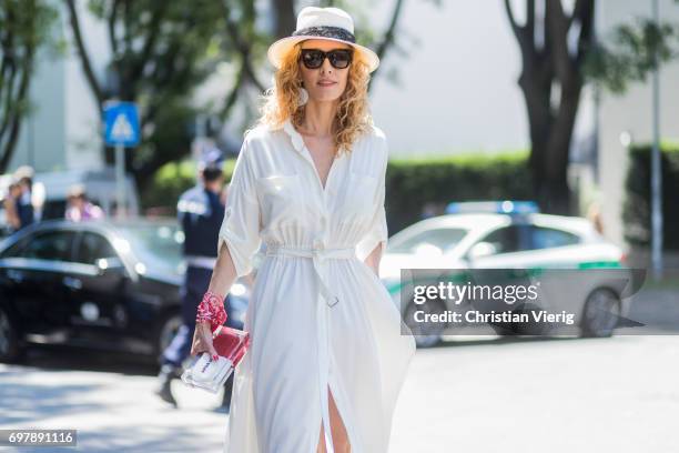 Elina Halimi wearing a white dress, straw hat, red boots is seen outside Armani during Milan Men's Fashion Week Spring/Summer 2018 on June 19, 2017...