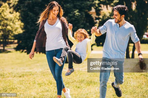 ouders die hun dochter swingende in de lucht - child park stockfoto's en -beelden