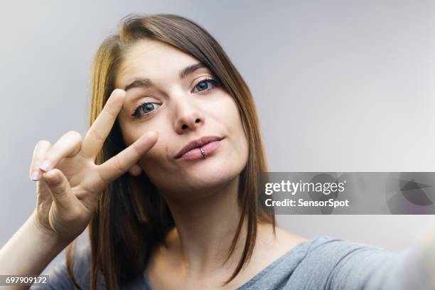 hermosa mujer hablando selfie sobre fondo gris. - gesto de victoria fotografías e imágenes de stock