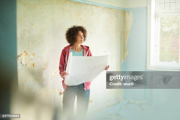 planning van haar nieuwe huis - vrouw behangen stockfoto's en -beelden