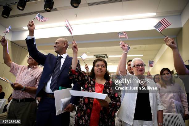 Newly naturalized citizens wave American flags after being sworn in as American citizens during a naturalization ceremony on June 19, 2017 in San...