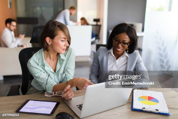 unternehmerinnen mit laptop, digital-tablette und diagramm papiere zusammen - super computer stock-fotos und bilder