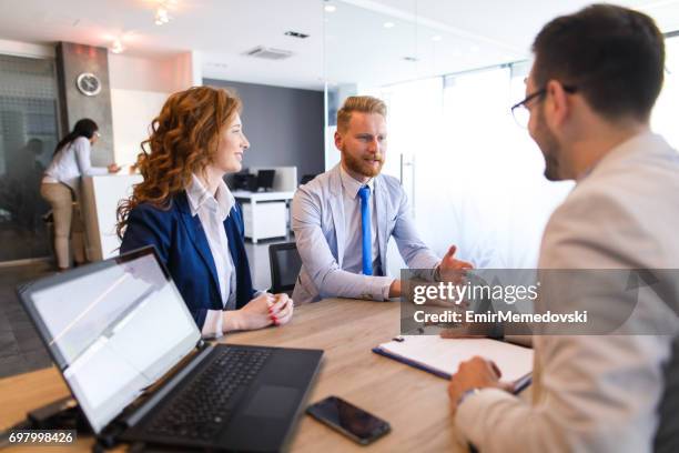 融資担当者に話している若いカ��ップル - business man sitting banking ストックフォトと画像