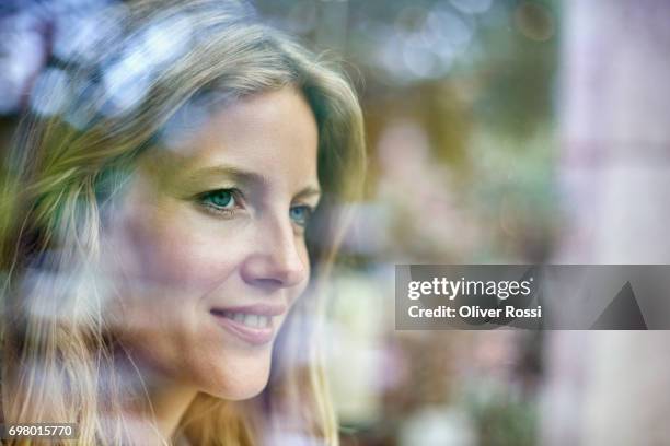 smiling woman looking out of window - looking away stockfoto's en -beelden