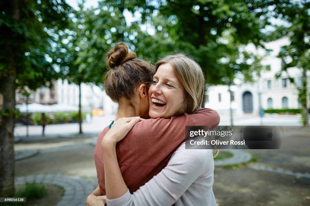 Two happy women hugging outdoors