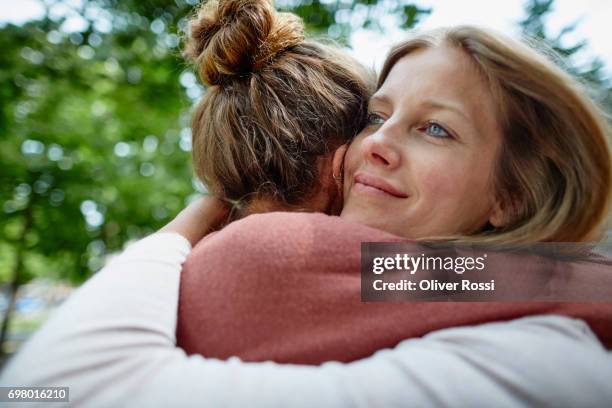 two women hugging outdoors - close to stock pictures, royalty-free photos & images