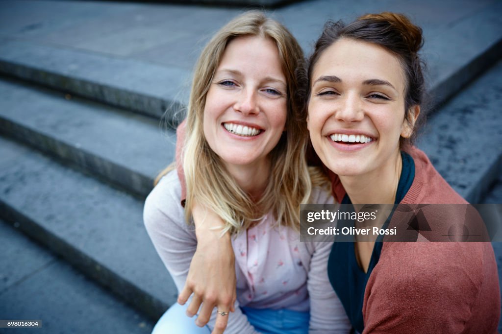 Portrait of two happy women embracing on stairs