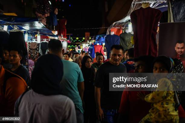 This picture taken on June 19, 2017 shows Malaysians walking through stalls selling headscarves and traditional "baju melayu" costumes, customarily...