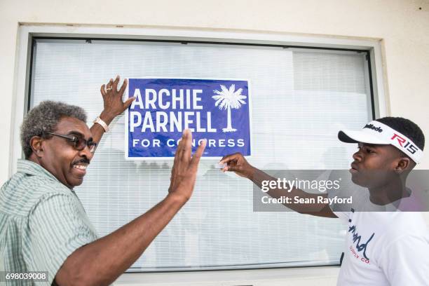 Ennis Bryant and his grandson DeShawn Vereen hang up a campaign sign for Democratic congressional candidate Archie Parnell June 19, 2017 in...