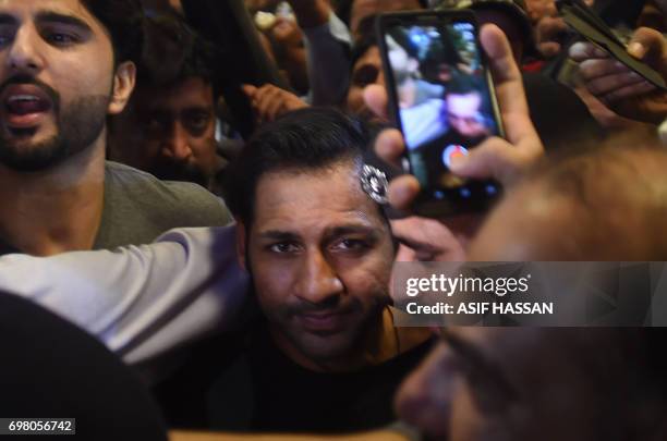 Pakistani cricket captain Sarfaraz Ahmed is surrounded by fans as he arrives from London outside the Karachi International airport in Karachi on June...