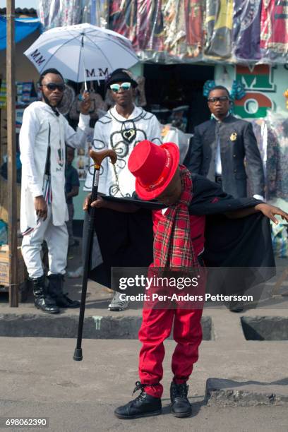 Olivier Kombe, a Sapeur, with his son outside one of their clothing shops on February 12, 2017 in Kinshasa, DRC. The word Sapeur comes from SAPE, a...