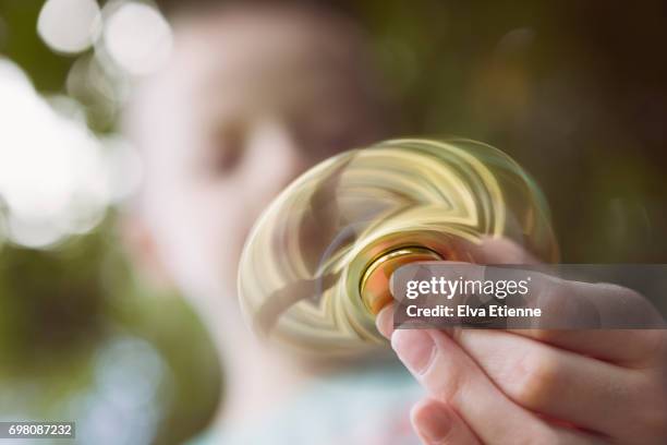child holding a moving fidget spinner - spinner stock pictures, royalty-free photos & images