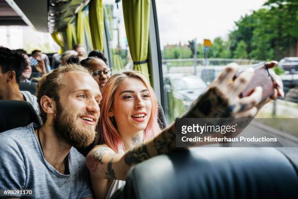 couple recording their journey using smartphone, travelling on the bus - rosa germanica foto e immagini stock