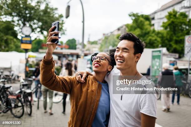 young tourist couple taking a photo of themselves - tourist couple fotografías e imágenes de stock