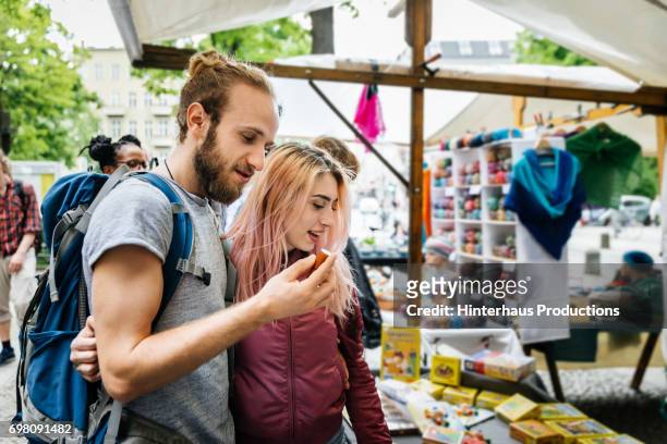 backpacking couple exploring local market"u2019s wares - marché de plein air photos et images de collection