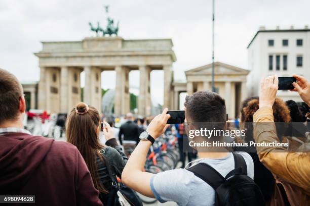 group of people travelling together take pictures of brandenburg gate - brandenburger tor stock pictures, royalty-free photos & images