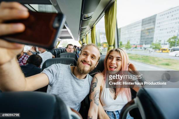 couple take selfie together as they travel on a bus - bus interior stock-fotos und bilder