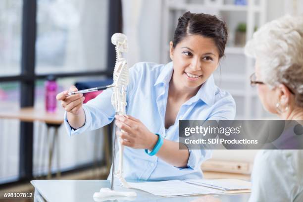 jonge chiropractor legt behandelplan senior patiënt - chiropractor stockfoto's en -beelden