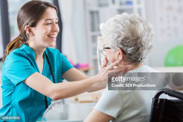 la enfermera utiliza humor al palpar el cuello del paciente mayor - head injury fotografías e imágenes de stock