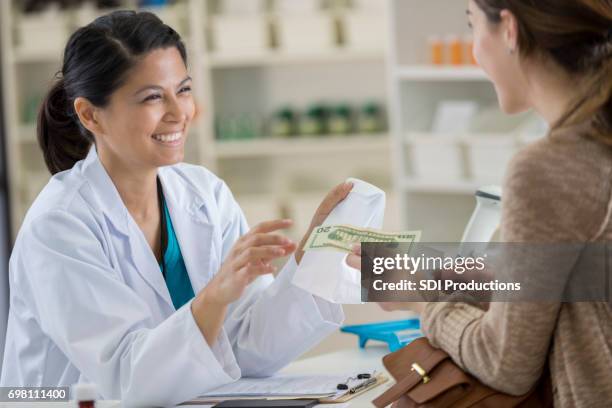 young female pharmacy customer pays for medication - paying cash stock pictures, royalty-free photos & images