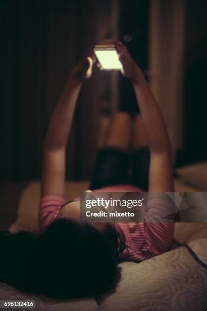 meisje met behulp van slimme telefoon in bed - girl in her bed stockfoto's en -beelden