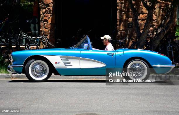Man drives his 1960 Corvette convertible, with a factory Tasco Turquoise paint job, along a street in Aspen, Colorado.