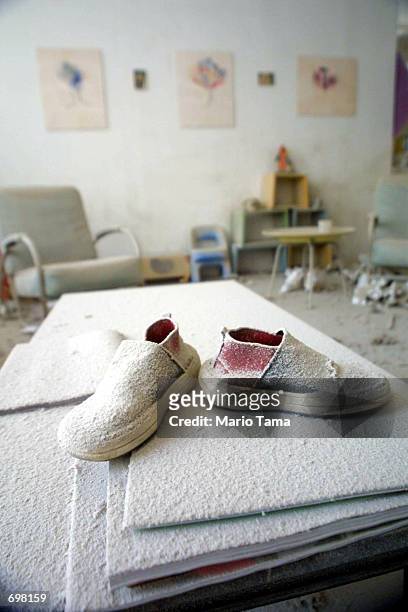 Pair of childrens shoes, covered in dust, stand on a table in a building near "ground zero" September 13, 2001 two days after two hijacked airplanes...