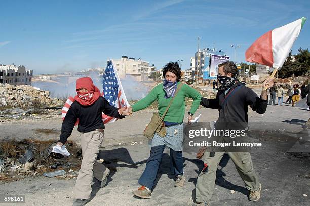 Palestinian youth assists a young woman blinded by tear gas who was part of a small international group of protesters that advanced towards Israeli...