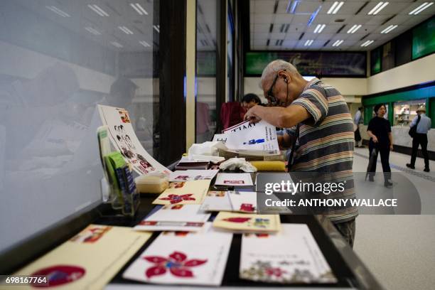 Stamp collector Lok Ka-chung looks through envelopes that he designed to send with a stamp issued to mark 20 years since the city was handed back to...