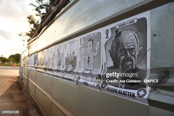 View of posters on a wall showing caricatures of various football related celebrities including Ricardo Texeira, Ronaldo, Jerome Valcke, Familia...
