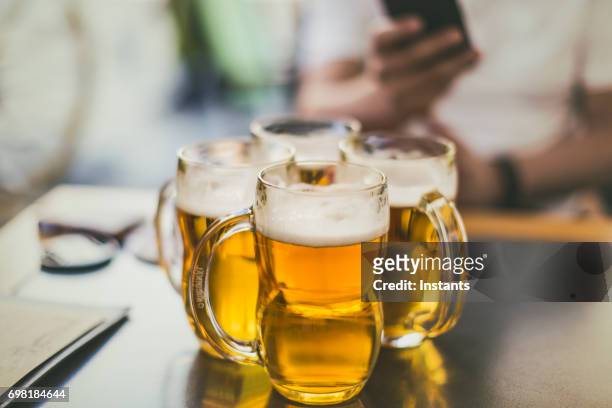 four pilsner beer mugs on a table, as shot in prague. - lager stock pictures, royalty-free photos & images