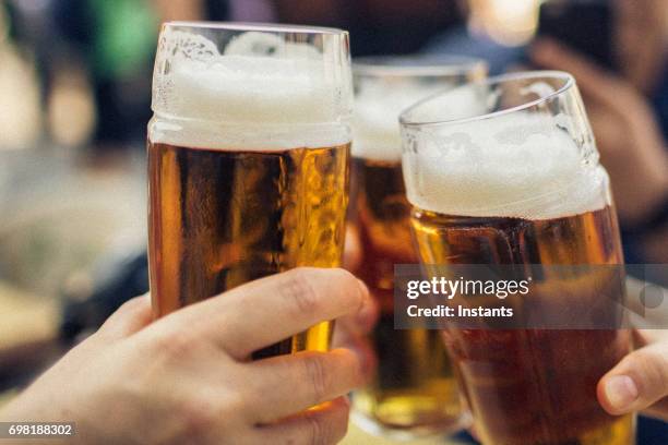 in prague, three friends cheering on good news with glasses of pilsner beer. - pale ale stock pictures, royalty-free photos & images