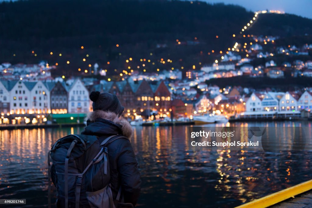 A man standing in front of Bergen havn with traditional wooden buildings in Bryggen in the background