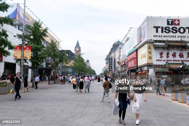 Tourists and shoppers walk on the Wangfujing business street. As the largest state-owned department store group, Wangfujing Group made 5.25 billion...
