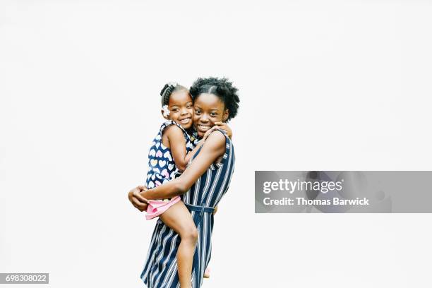 smiling older sister standing against white background holding and hugging younger sister - sibling support stock pictures, royalty-free photos & images