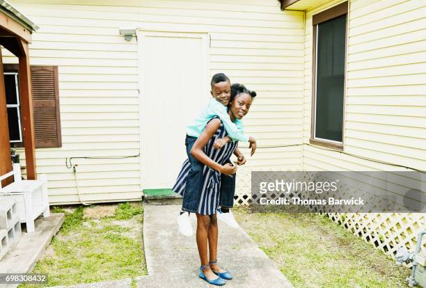 Smiling young woman carrying younger brother on back