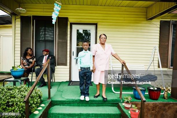 young boy standing with grandmother on front porch of home - black family reunion stock pictures, royalty-free photos & images