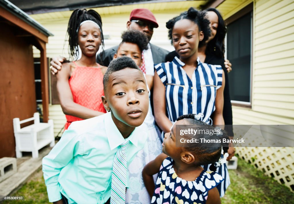 Young boy posing for portrait with family members in front of house