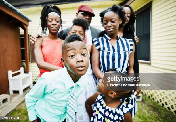 young boy posing for portrait with family members in front of house - black family reunion stock pictures, royalty-free photos & images