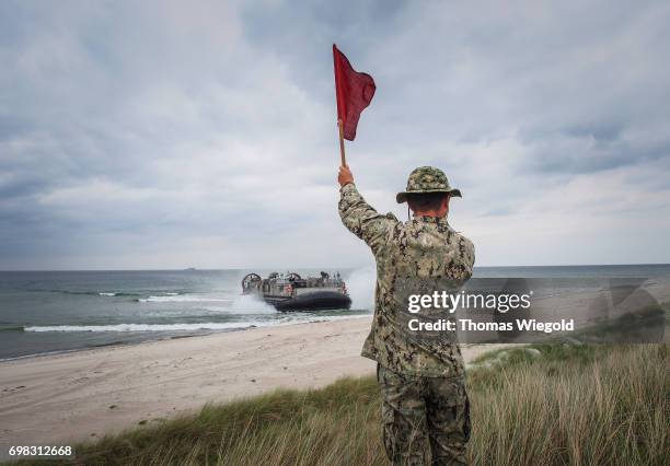 Soldier waves signal flags when a Landing Craft Air Cushion is driving to the beach during an Amphibious Landing Exercise on June 08, 2017 in...