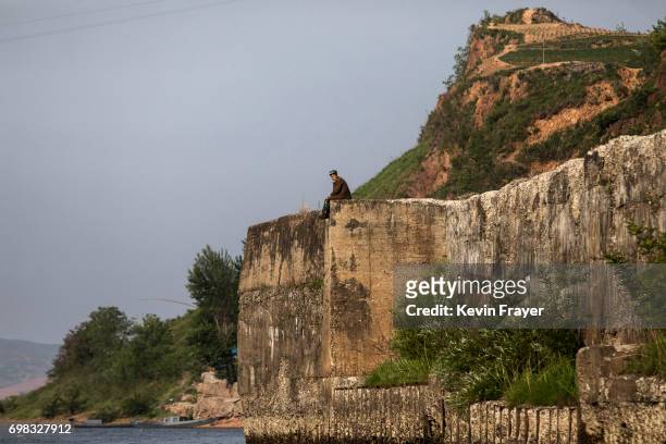 North Korean sits on a wall on the Yalu river north of the border city of Sinuiju, North Korea across from Dandong, Liaoning province, northern China...