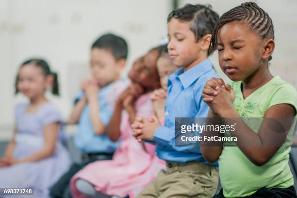 praying together in sunday school - child praying school stock pictures, royalty-free photos & images
