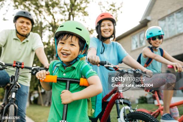 family holidays - family riding bikes with helmets stock pictures, royalty-free photos & images