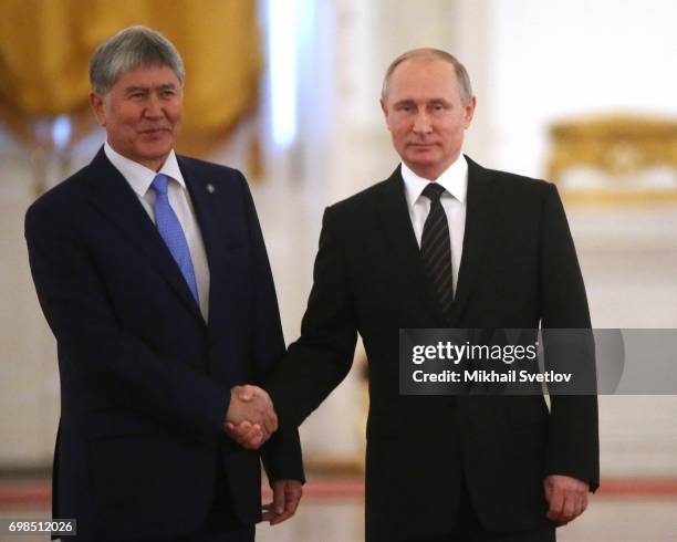 Russian President Vladimir Putin greets Kyrgyz President Almazbek Atambayev during their talks at the Grand Kremlin Palace in Moscow, Russia, June...