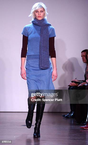 Delfine wears a blue denim sweater dress, a black long sleeve rouched ballet top, black tall lace-up boots and a blue scarf during the Kenneth Cole...