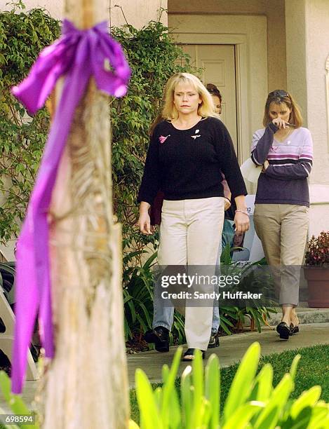 Purple ribbon hangs from a tree as Brenda van Dam , mother of missing 7-year-old Danielle van Dam, walks out of her house along with Diane Halfman to...