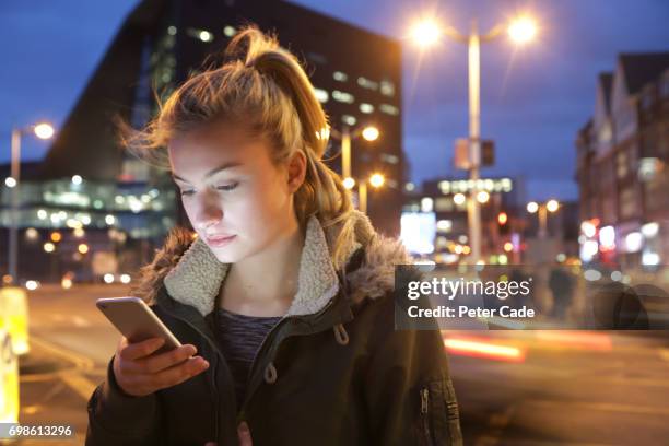 woman in city at night looking at phone - plymouth devon stock-fotos und bilder