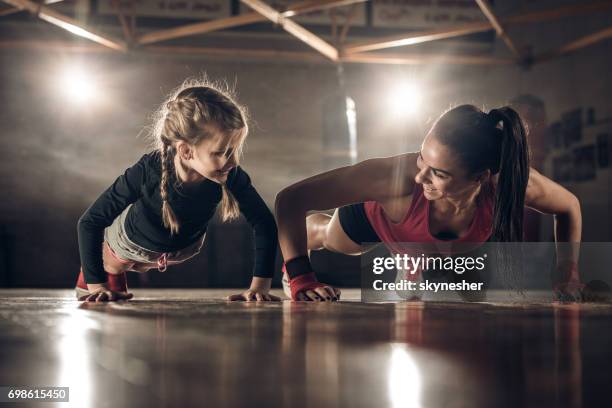 gelukkig vrouwelijke coach en meisje doen push-ups in een healthclub. - kids boxing stockfoto's en -beelden