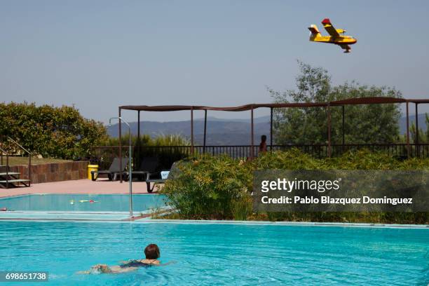 Woman enjoys a swim as a firefighter plane flies over after a wildfire took dozens of lives on June 20, 2017 in Mega Fundeira village, near Picha, in...