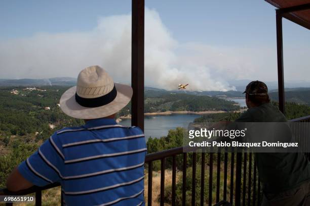 Men watch firefighter planes battling a fire after a wildfire took dozens of lives on June 20, 2017 in Mega Fundeira village, near Picha, in Leiria...